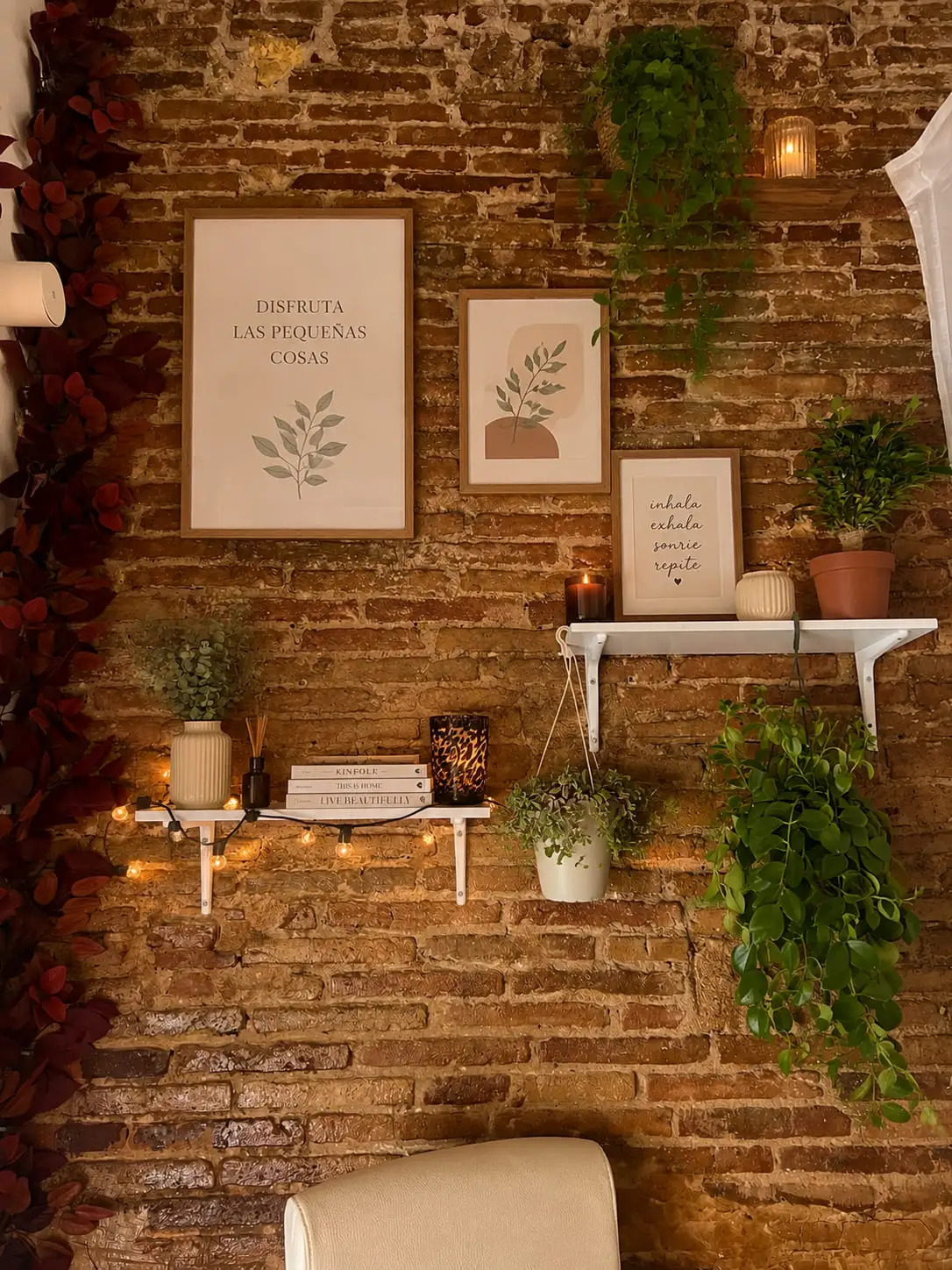 Pared de ladrillo con láminas enmarcadas, plantas y velas encendidas