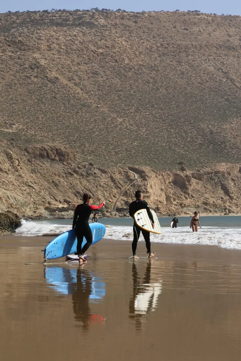 Dos surfistas caminando hacia el agua con sus tablas bajo el brazo