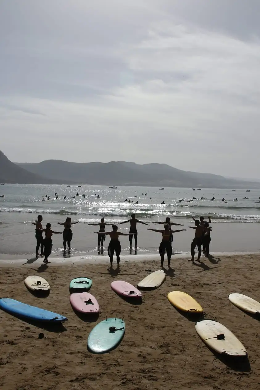 Calentamiento en la orilla antes de entrar al agua, con las tablas sobre la arena